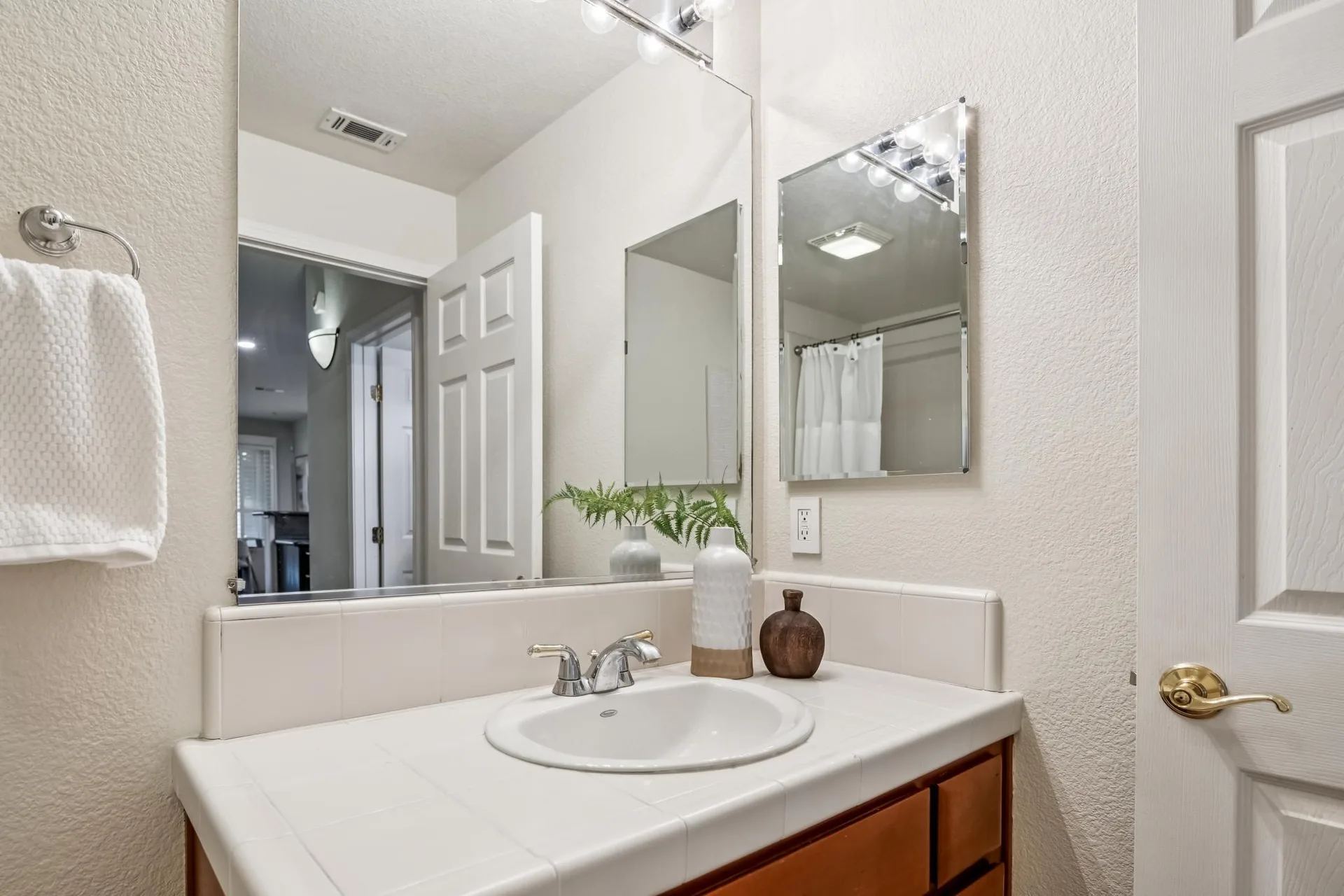 Bathroom vanity with white tile counter, mirror and chrome fixtures