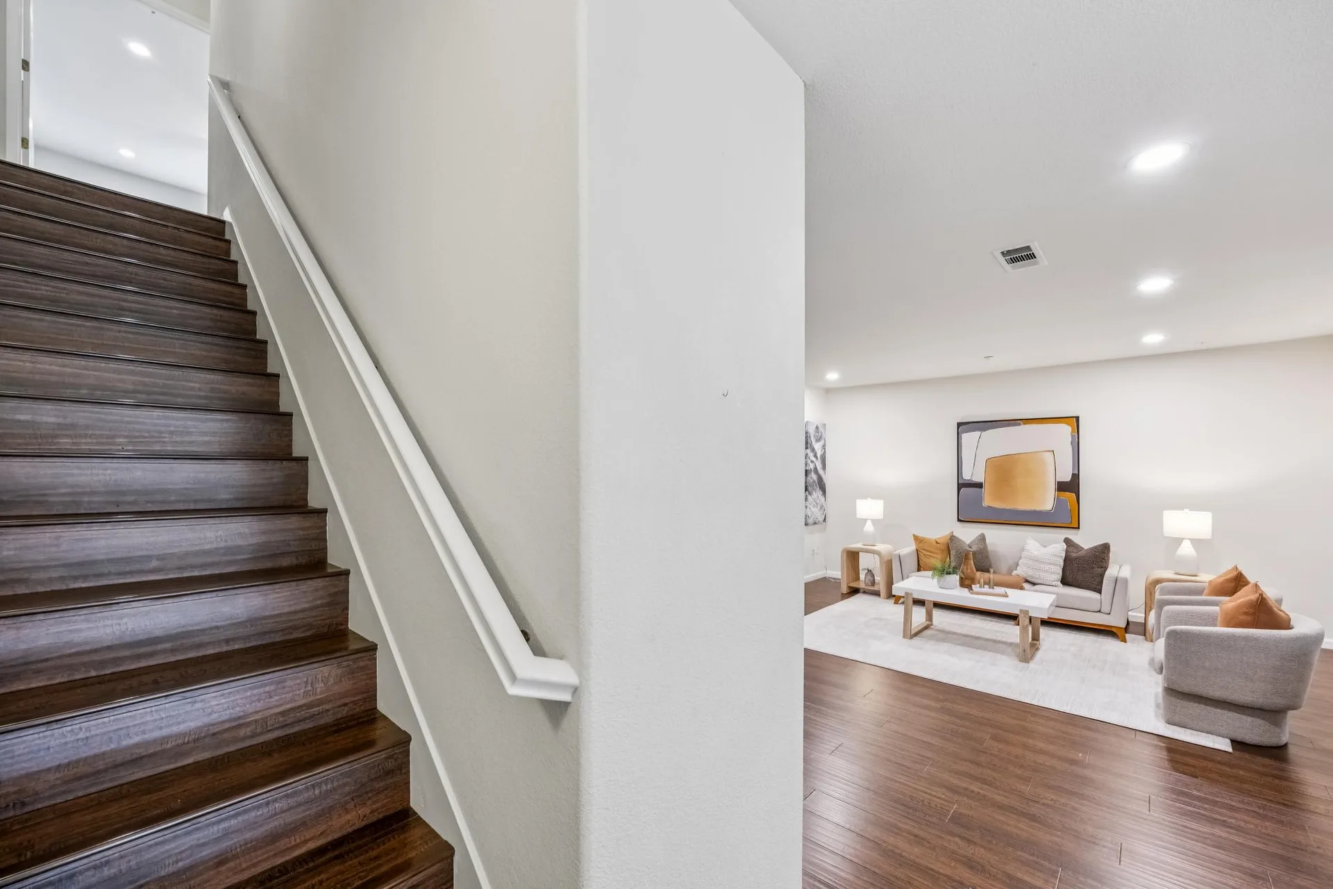 View from the staircase into the living room with white railing and dark wood treads