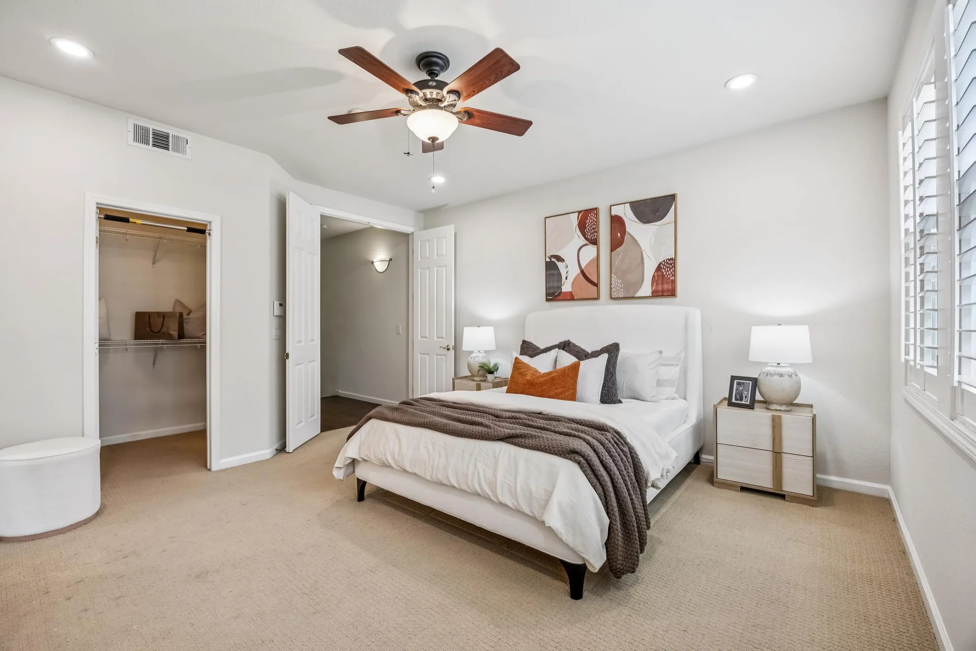 Primary bedroom suite with upholstered bed and white plantation shutters