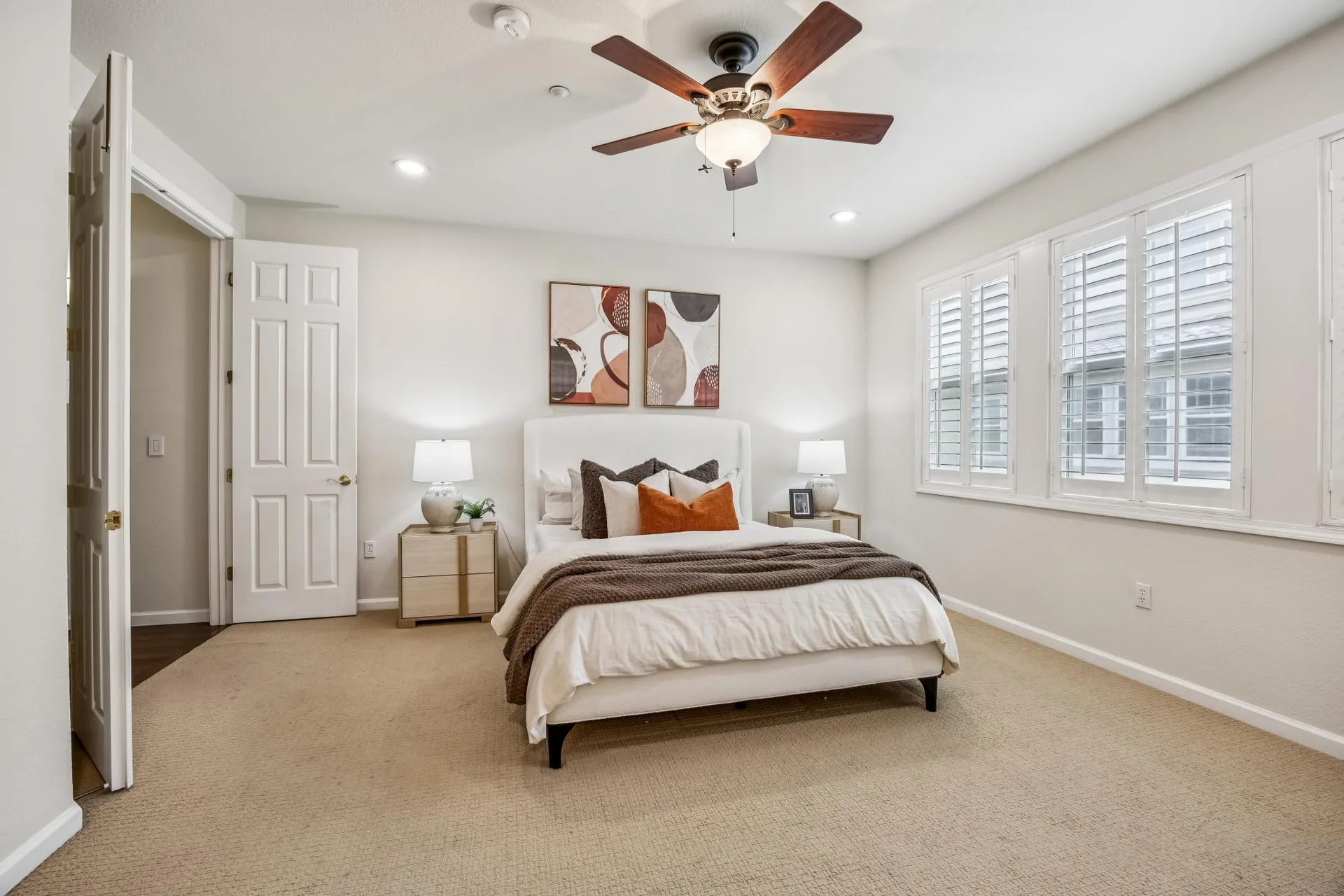 Spacious primary bedroom with plantation shutters and abundant daylight