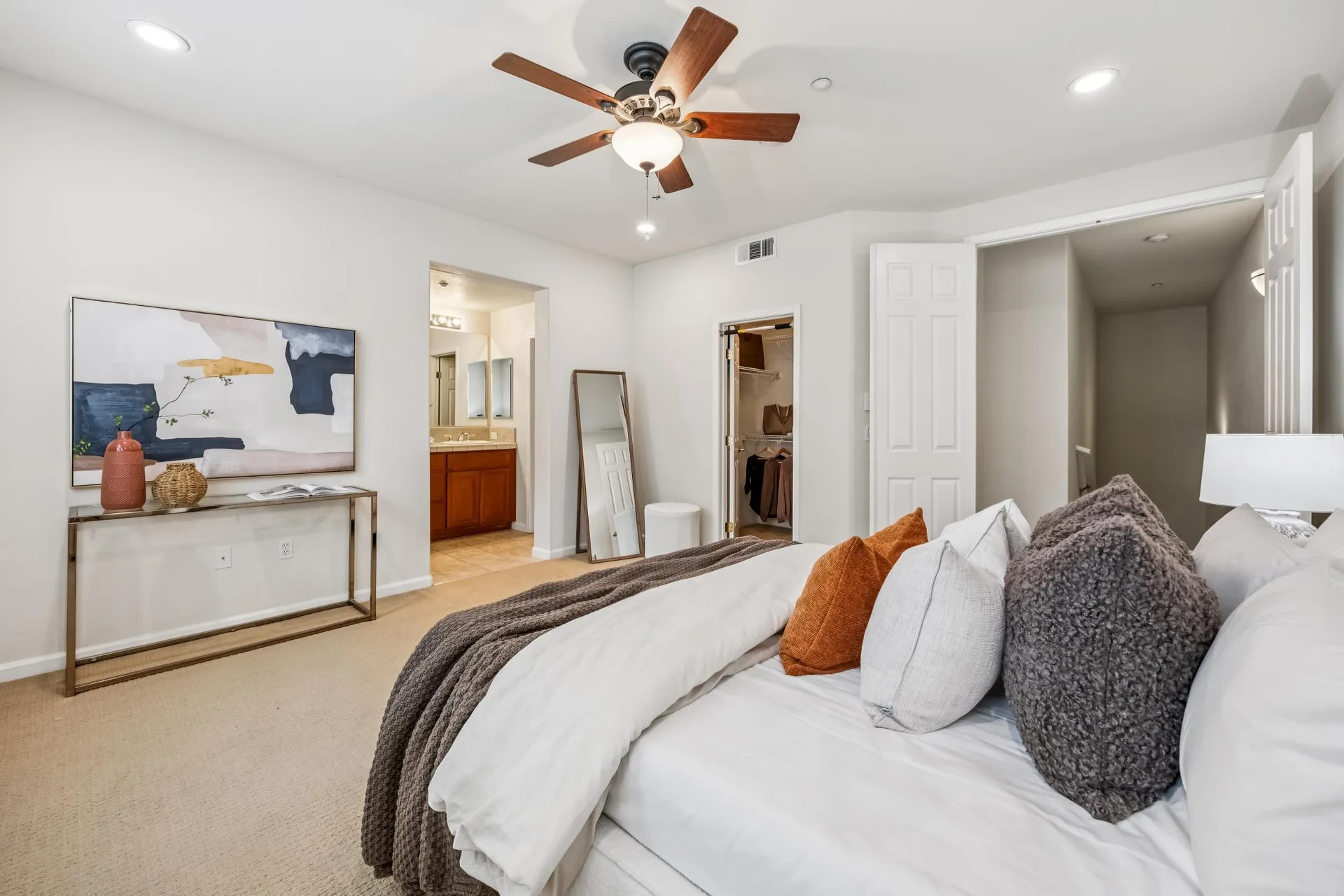 Primary bedroom with console table, floor mirror and ceiling fan