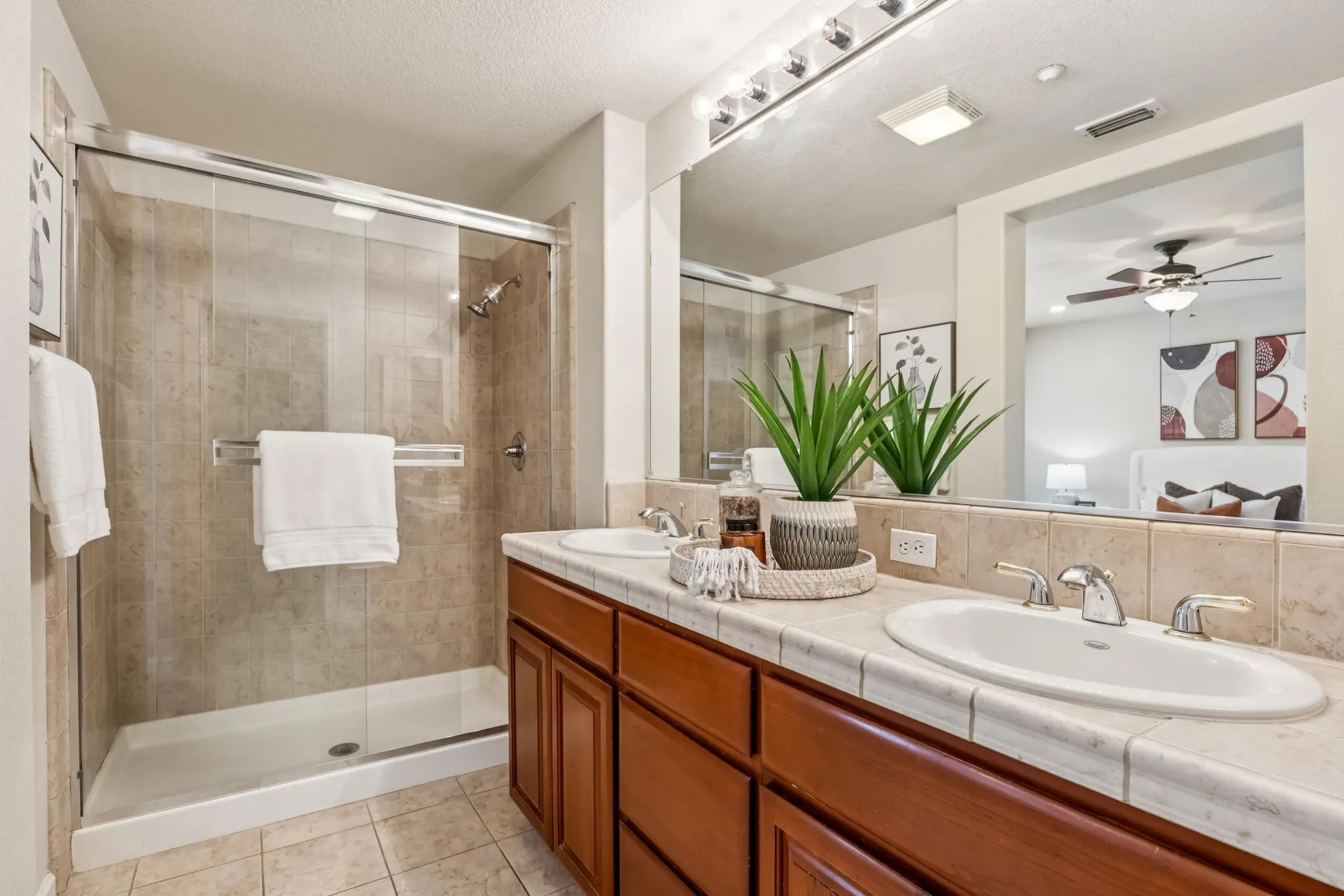 Primary bathroom vanity with stone-look tile and glass shower door