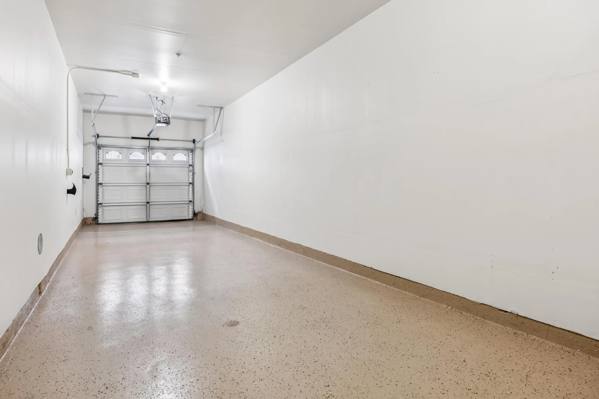Attached two-car tandem garage with white walls and epoxy flooring