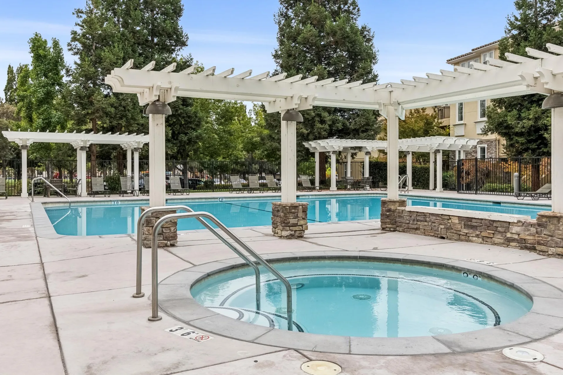 Community pool and spa with stone edging and lounge chairs