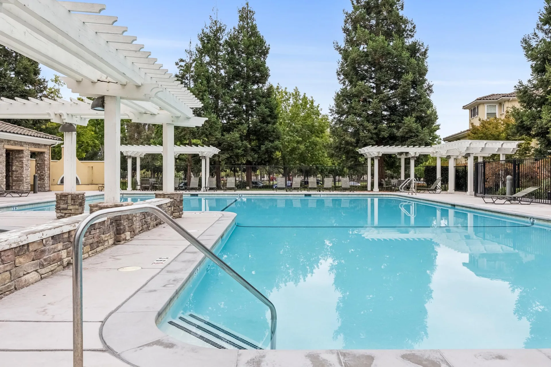 Community swimming pool with stone-accented columns and pergola
