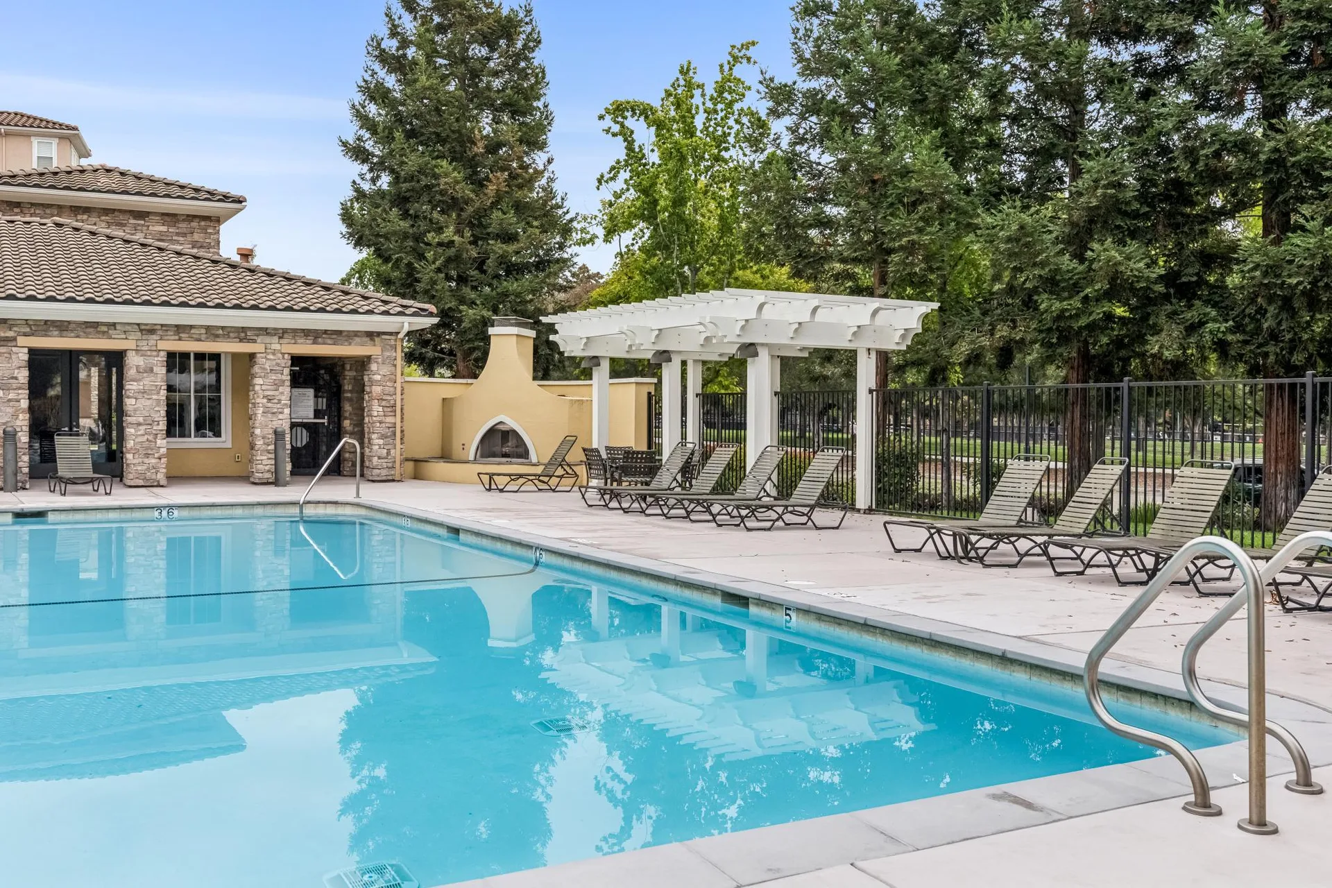 Pool deck with Mediterranean architecture and white wooden pergola