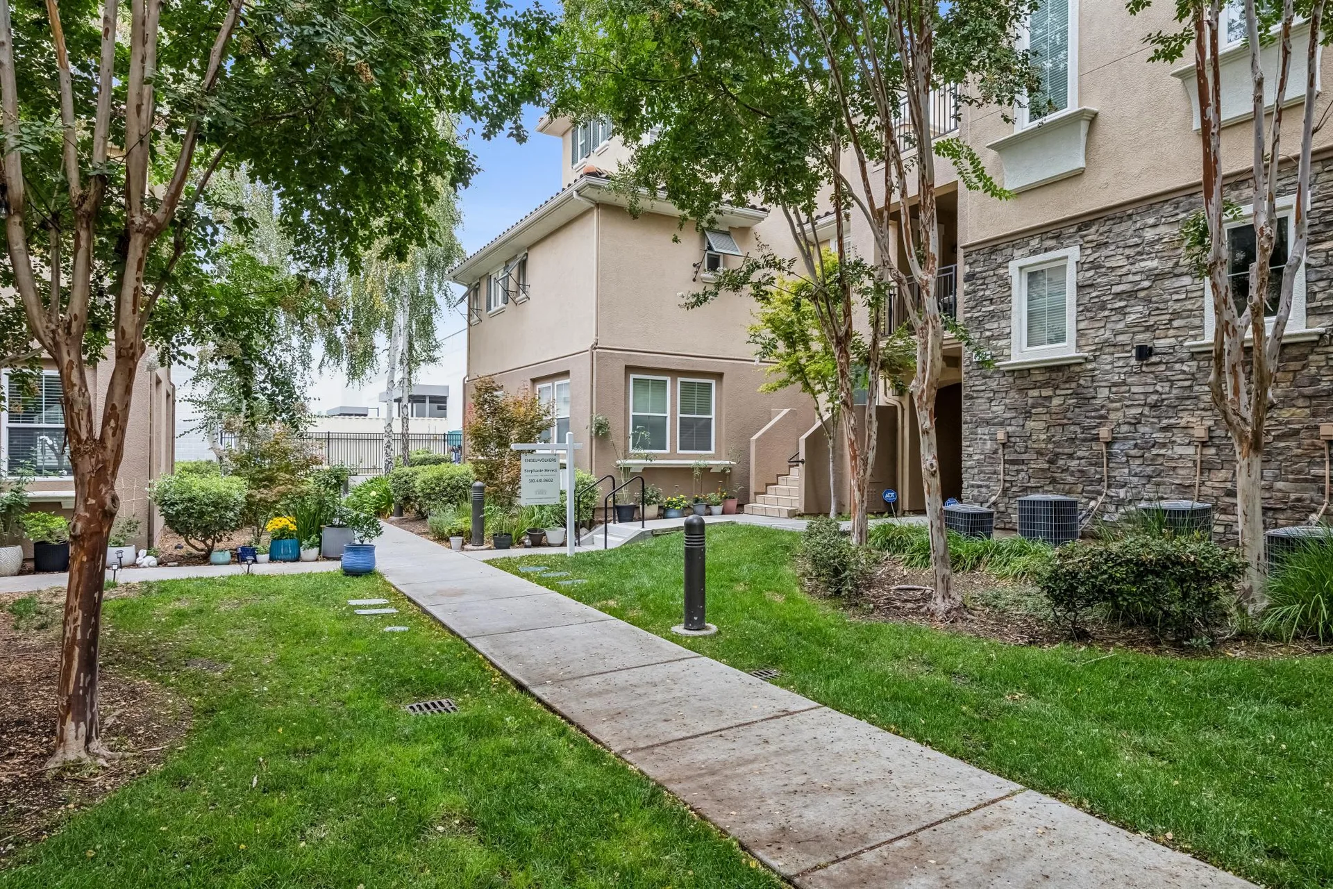 Common walkway along the townhome with lawn, potted plants and daylight