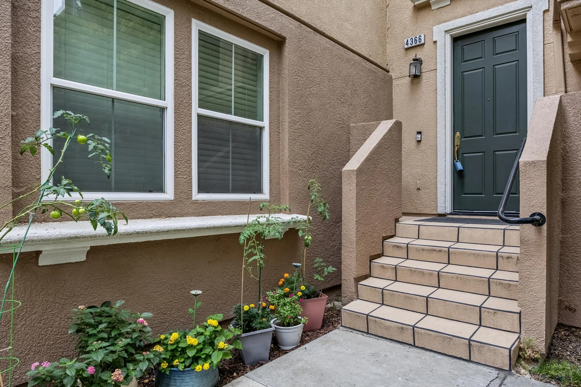 Front entry with dark green door, tiled stairs and metal railing