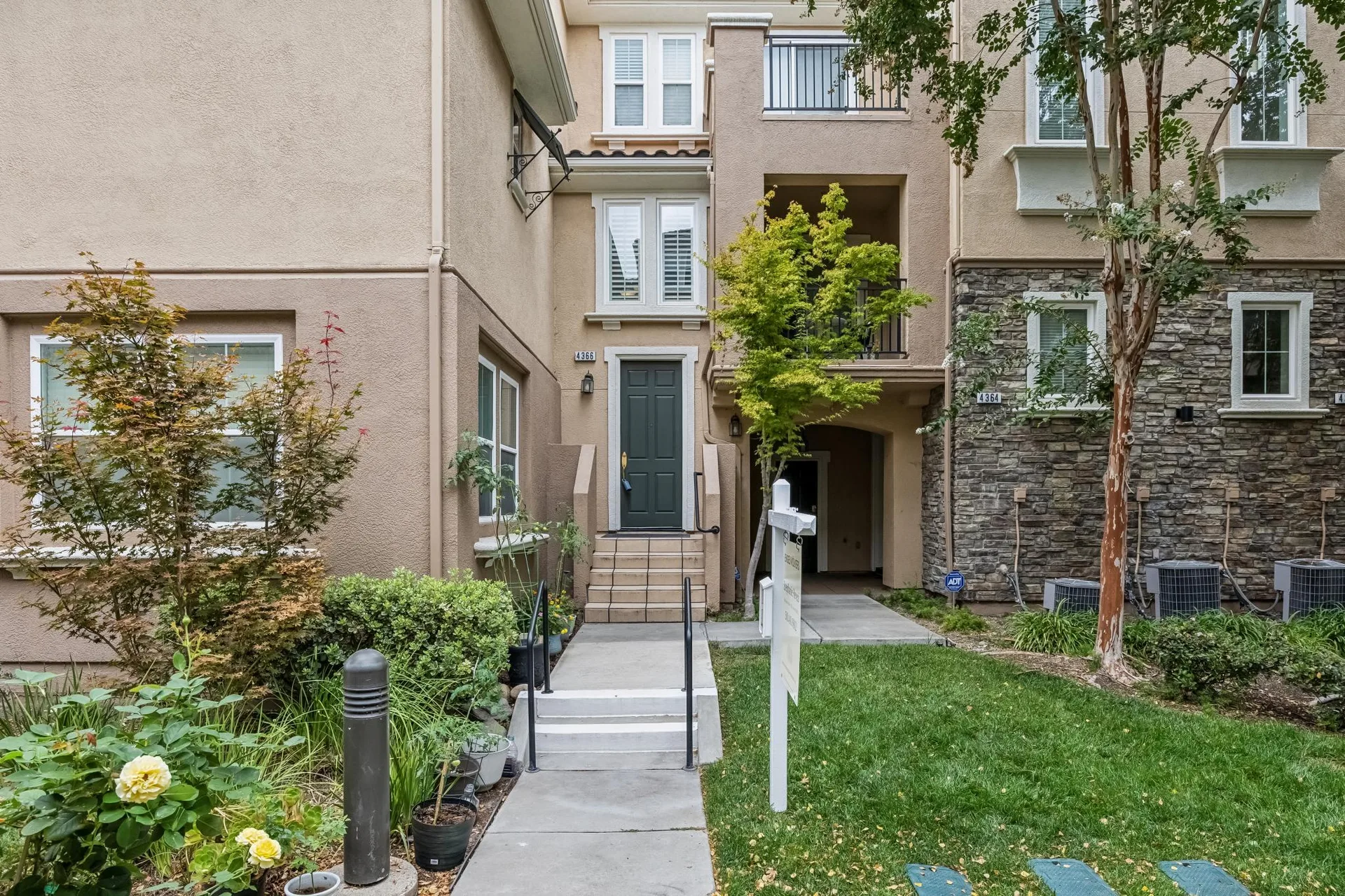 Straight-on view of the townhome entrance with tan stucco and stone veneer accents