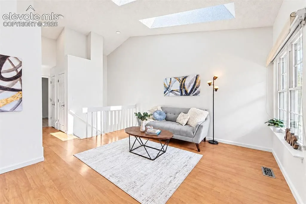 Vaulted living room with skylight and a view of the dining area