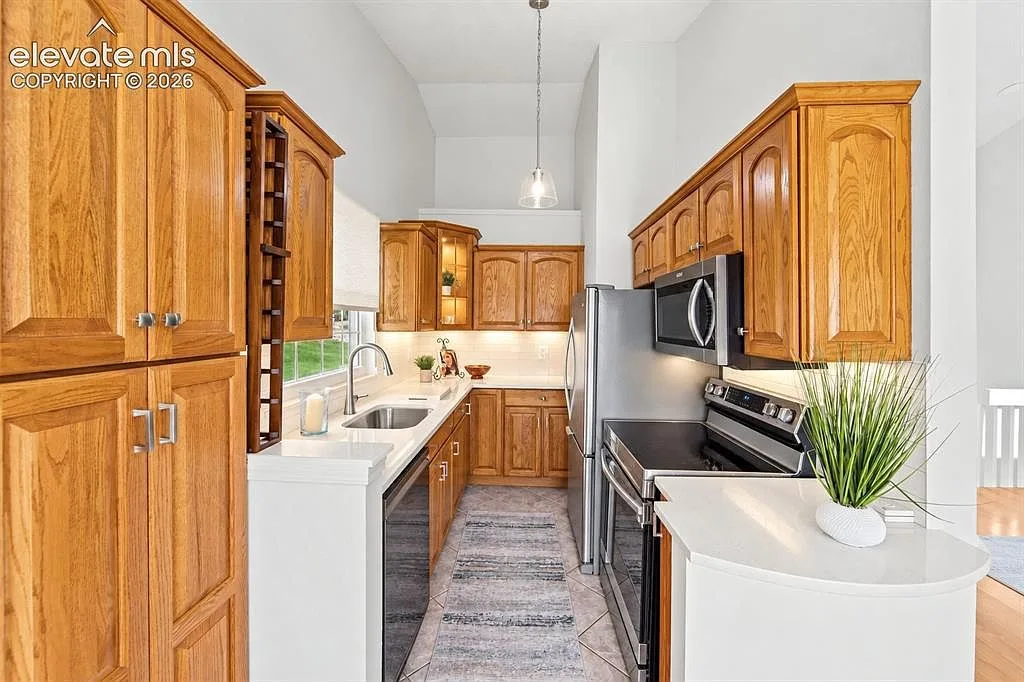 Galley kitchen with oak cabinetry, quartz counters, and subway tile