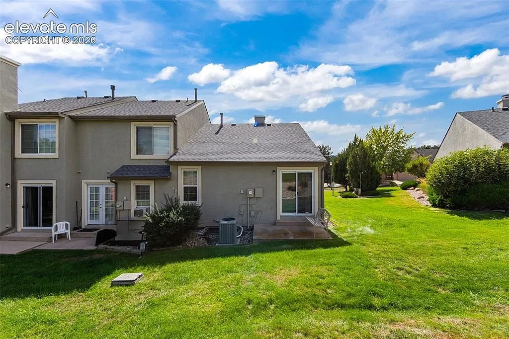 Rear exterior with a concrete patio and shared lawn