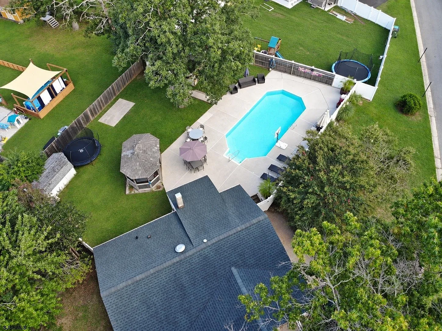 Aerial view of the fenced backyard with in-ground pool, patio, and gazebo