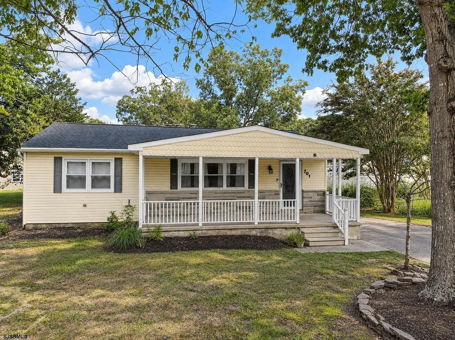Ranch home facade with a large covered front porch and scallop-shingle gable