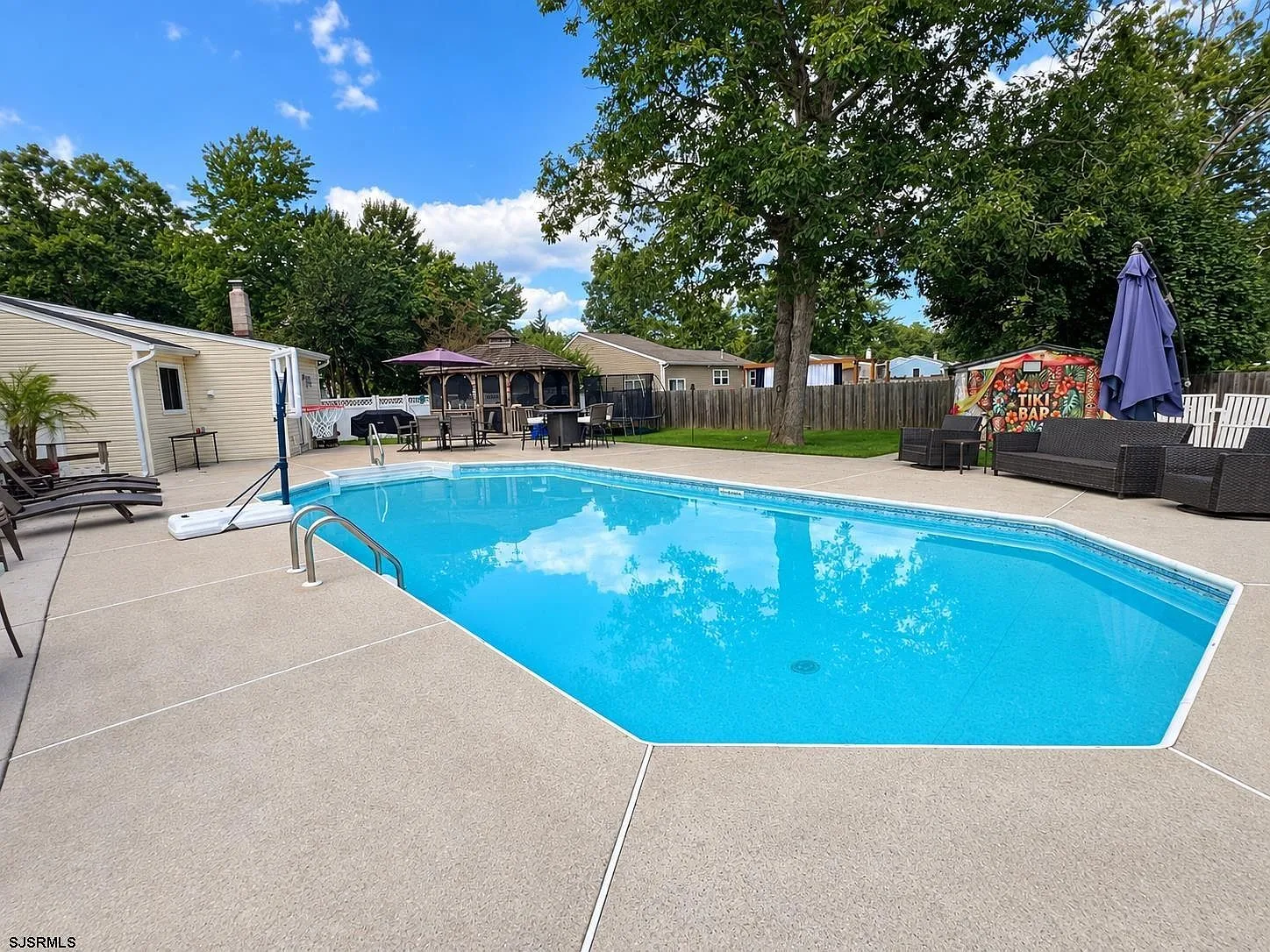 In-ground pool with patio loungers and mature trees at 701 Coventry Lane