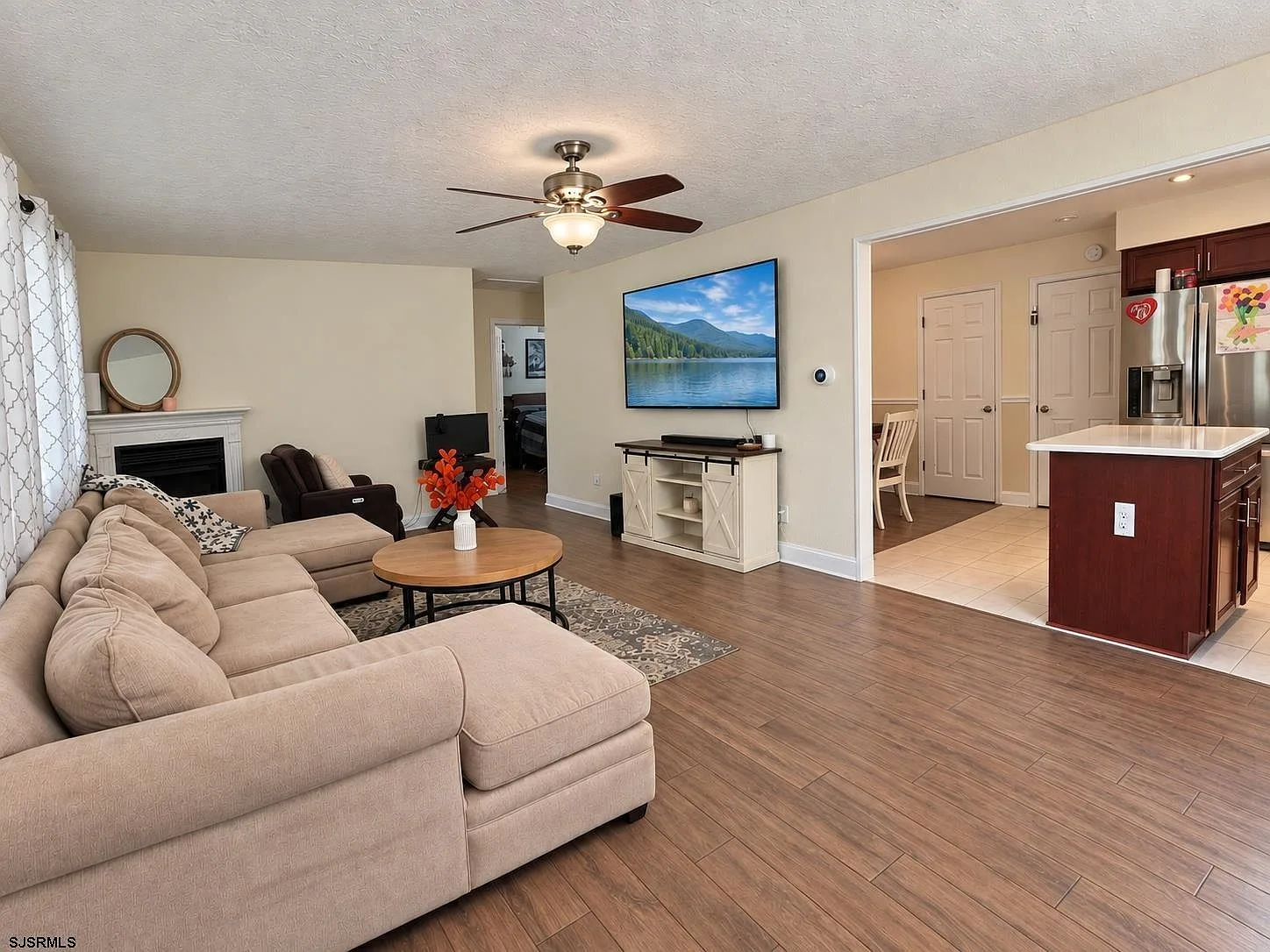 Open living room flowing toward the kitchen with wood-look flooring