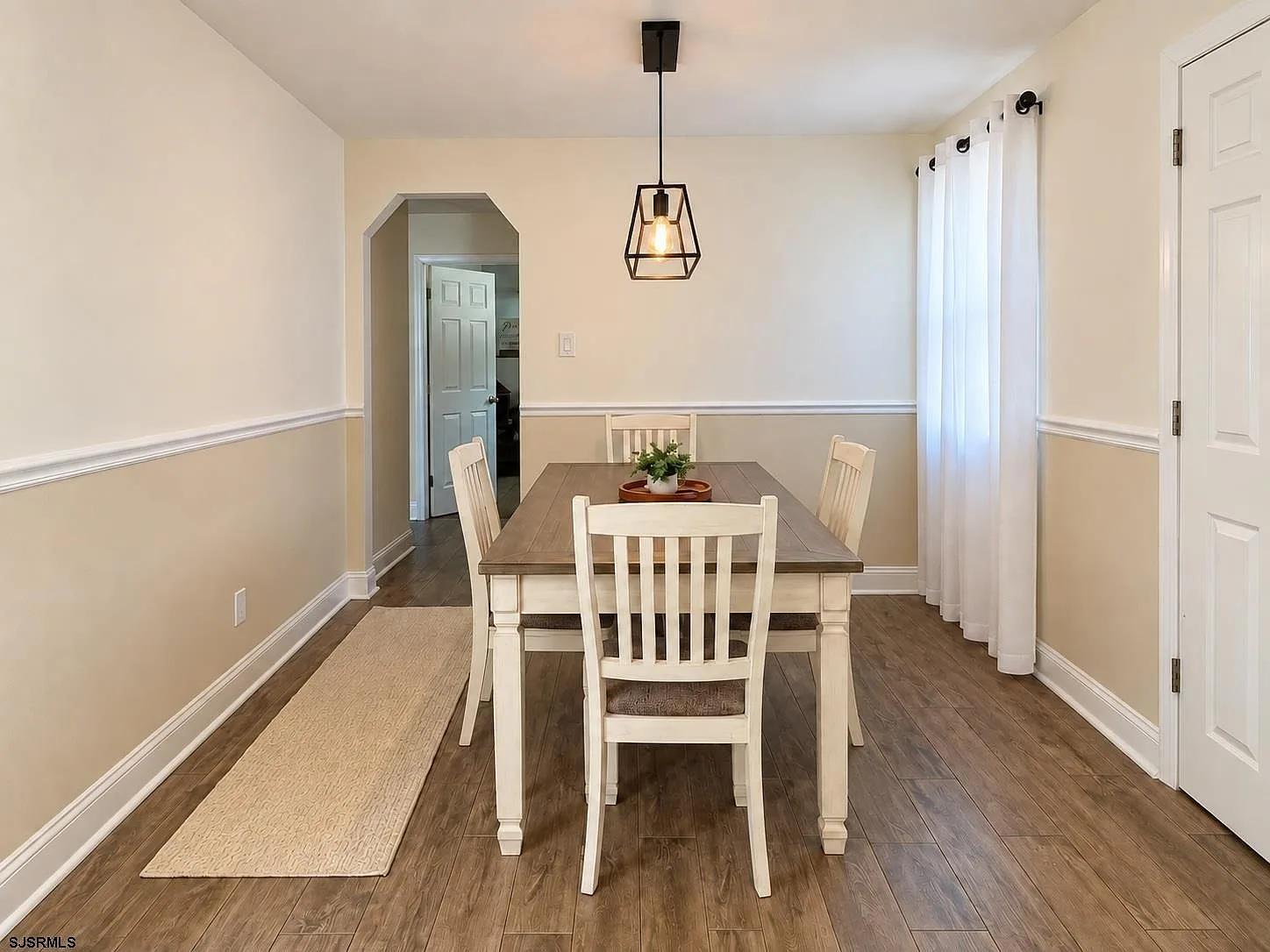 Dining room with two-tone walls, chair rail, and pendant light