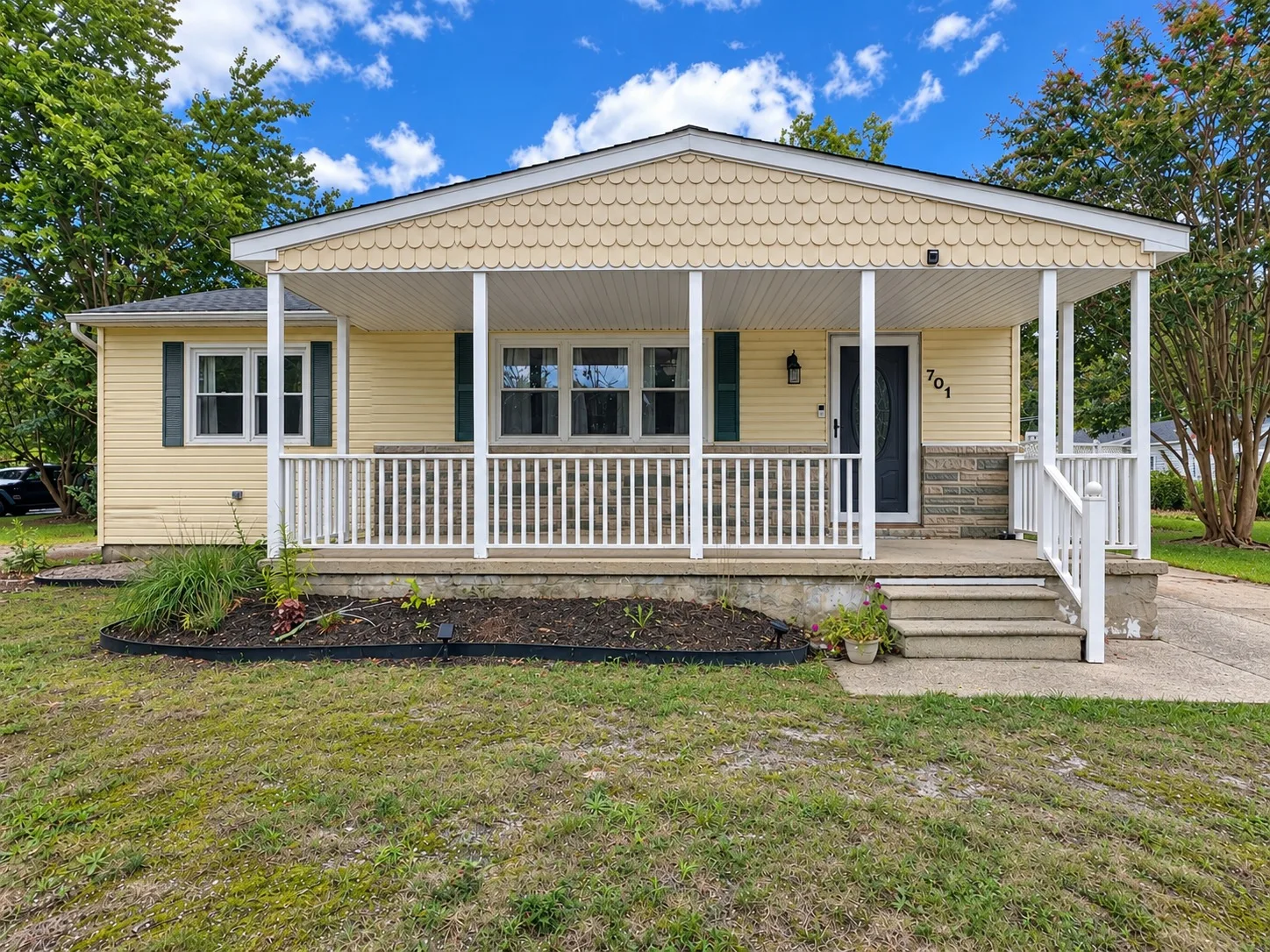 Straight-on view of the ranch home at 701 Coventry Lane with pale yellow siding, a covered front porch, and a scalloped gable
