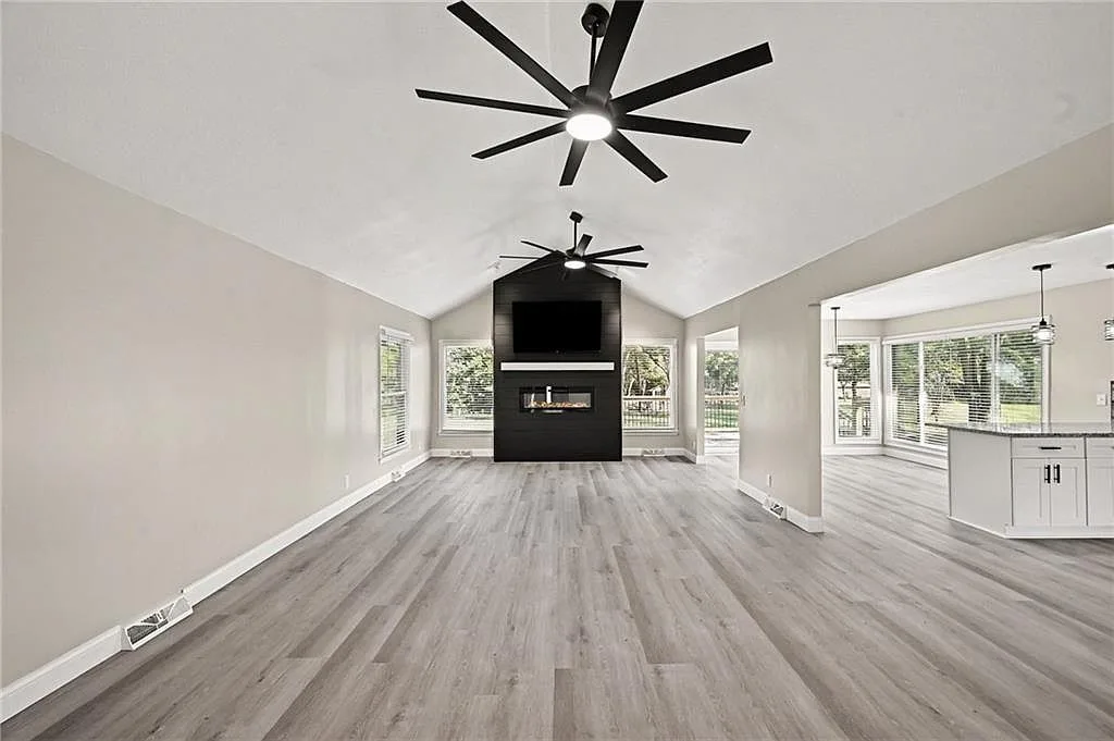 Renovated living room with vaulted ceiling, dark feature wall, fireplace and open sight line to the kitchen