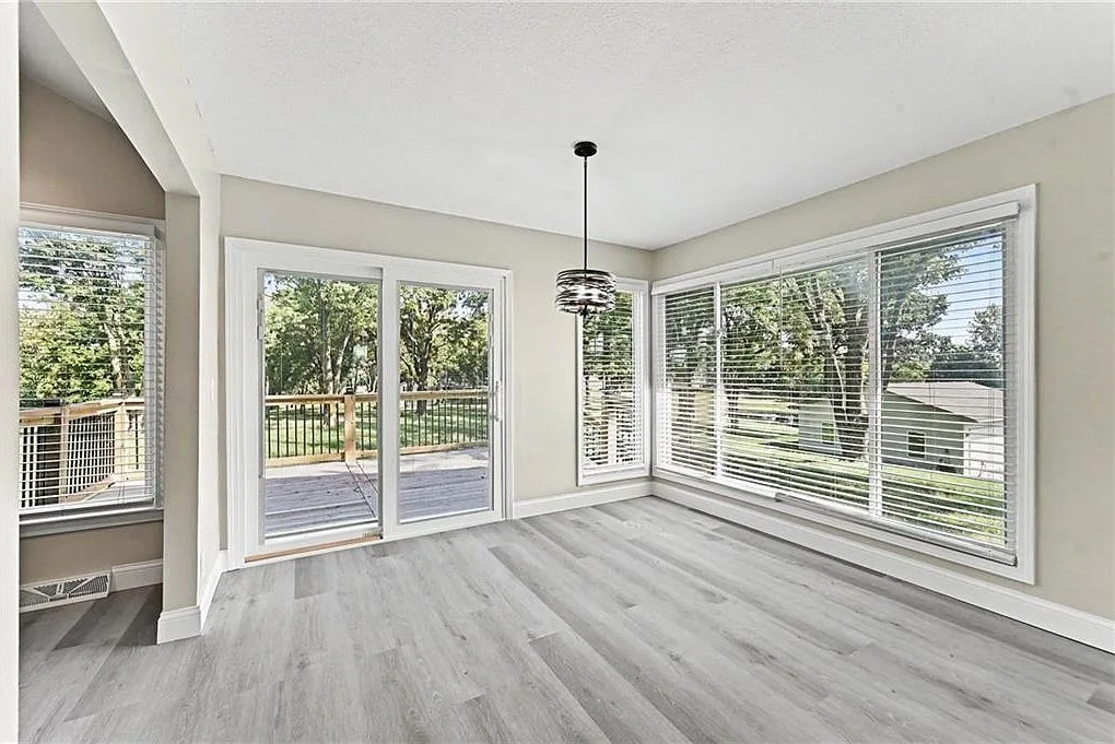 Sun-filled dining room with large windows, chandelier and light wood-look flooring