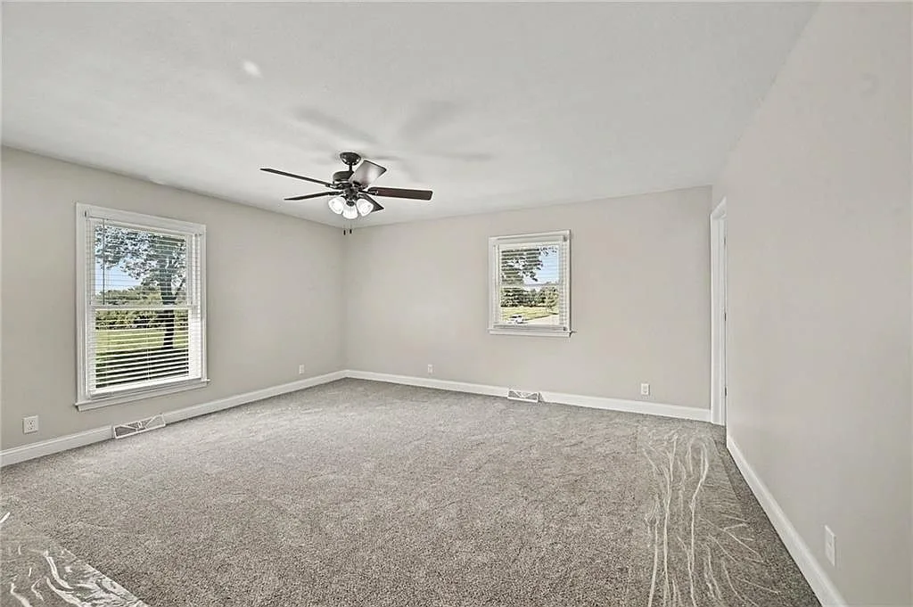 Spare bedroom with light grey walls, neutral carpet and bright natural daylight