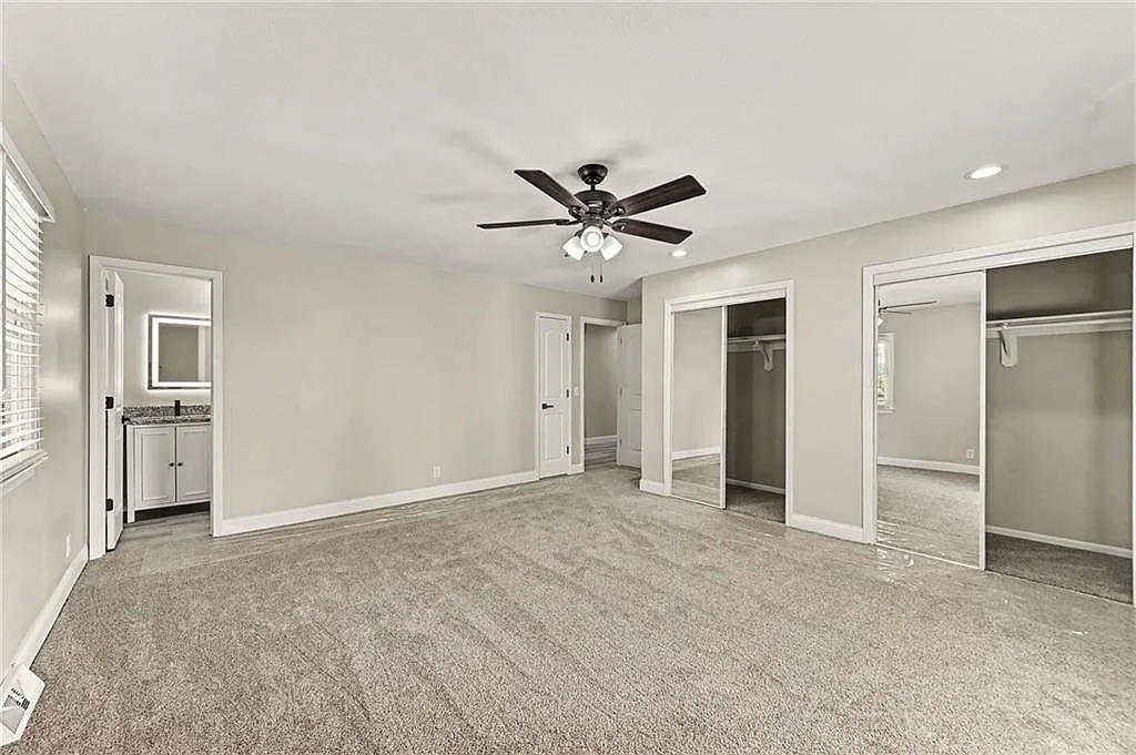 Renovated primary bedroom with neutral paint, carpet and mirrored closet doors