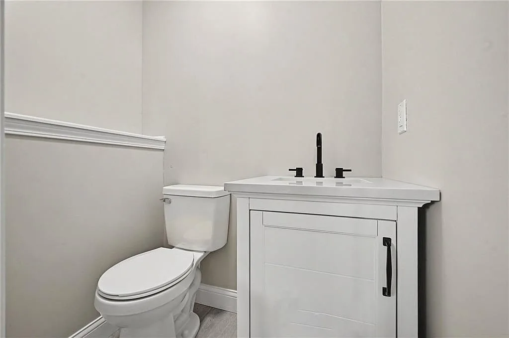 Half bath with white vanity, matte black faucet, chair rail molding and light grey walls
