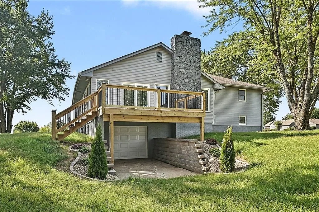 Backyard deck overlooking the lawn with the detached garage and tree line in the distance
