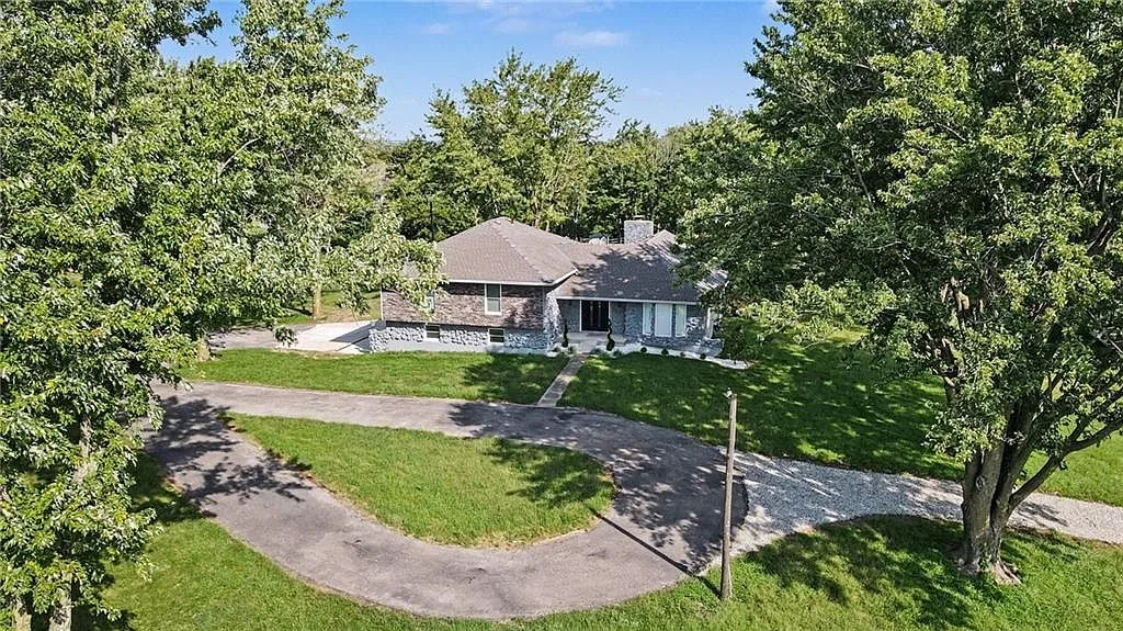 High-angle aerial of the ranch home, curved driveway and extensive mature landscaping