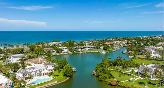 Aerial of Port Royal canal-front estates with pools, private docks, and moored boats leading to the ocean
