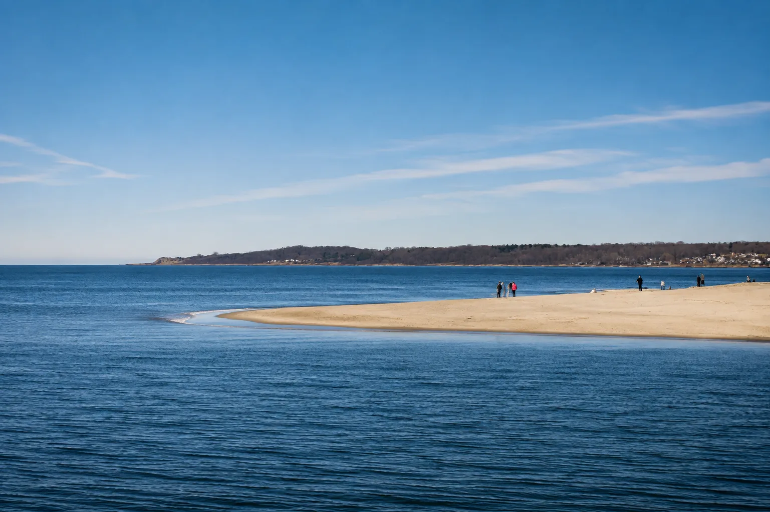 A sandy spit of North Shore beach stretching into deep blue ocean water