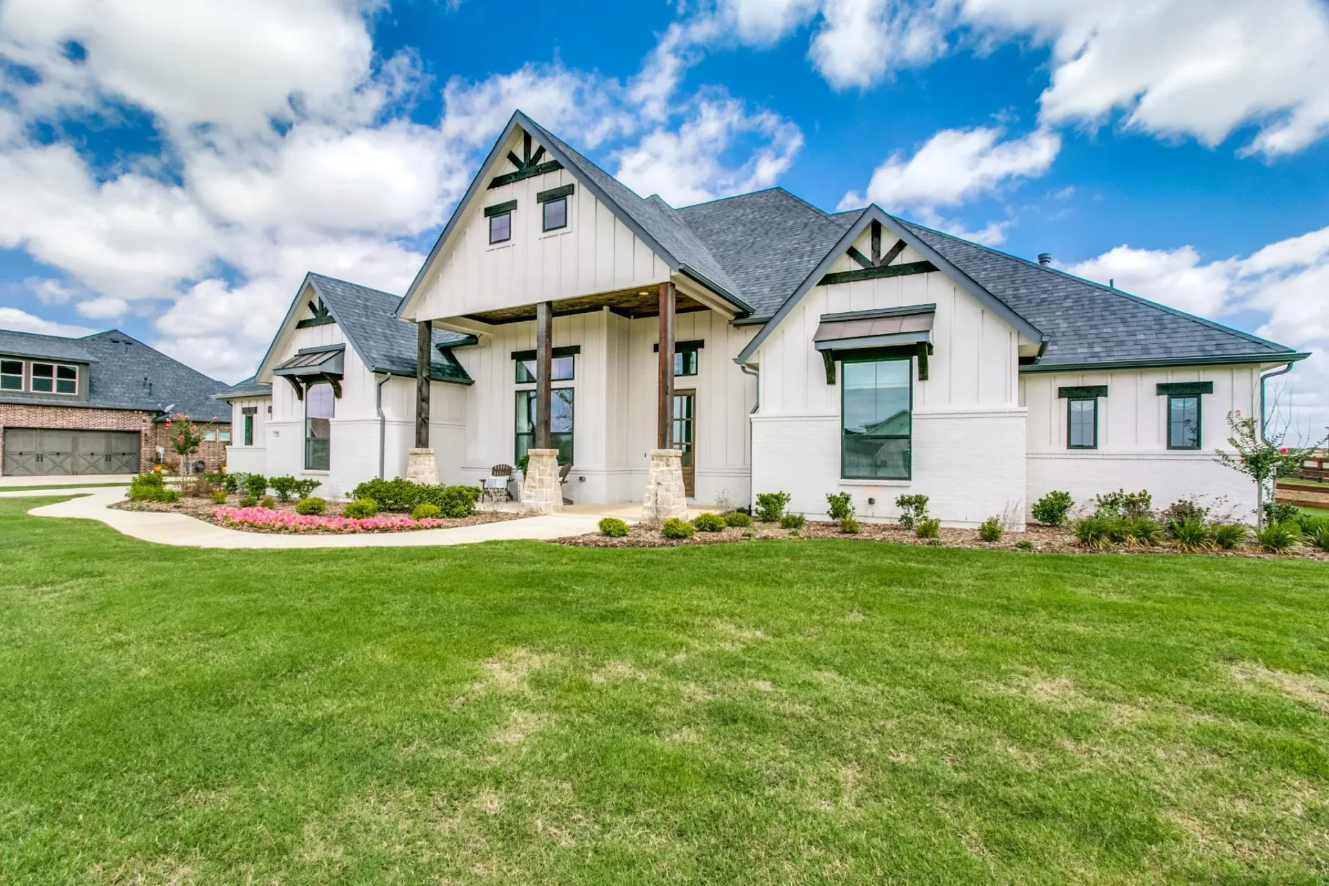 A white board-and-batten new-construction home with a dark roof in The Highlands of Northlake, Texas