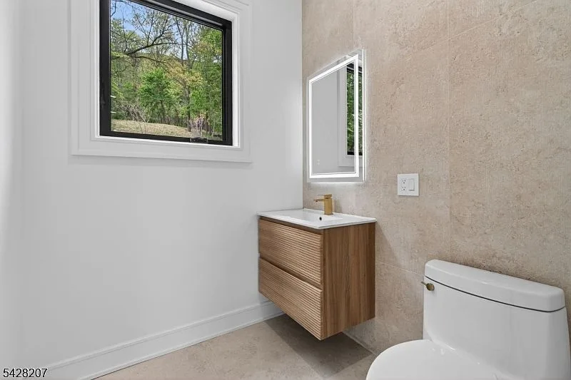 Powder room with floating wood vanity and matte gold faucet