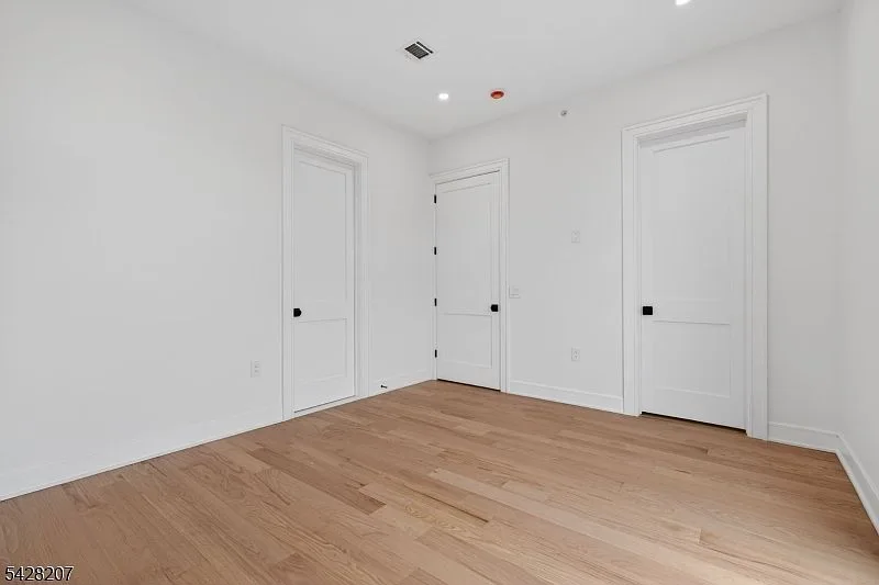 Bright third-floor bedroom with white walls and light hardwood floors