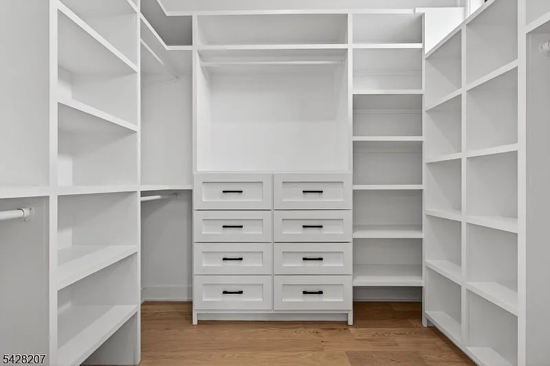 Walk-in closet with white built-ins and matte black hardware