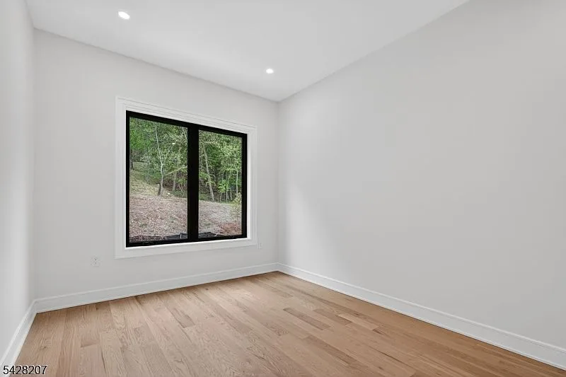 Corner bedroom with a large black-framed window and natural daylight