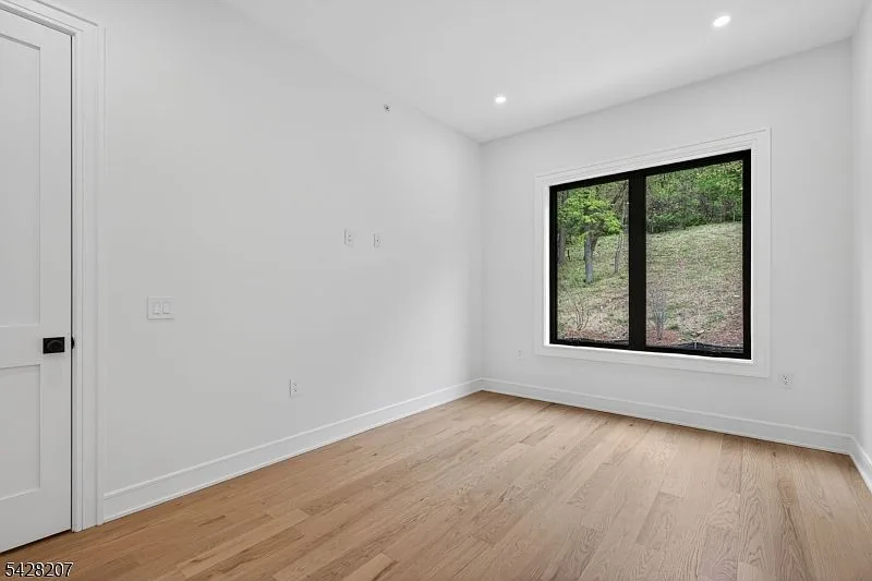 Bedroom with dark-framed window overlooking greenery