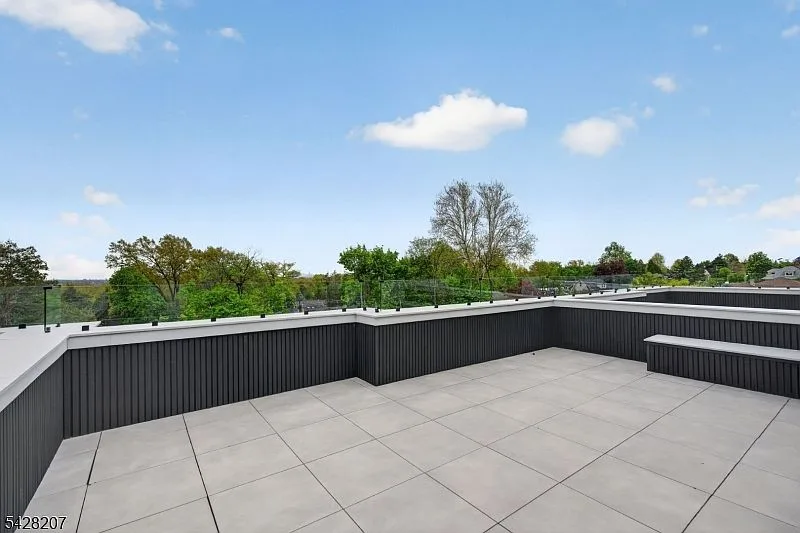 Private rooftop terrace with gray pavers and glass railings