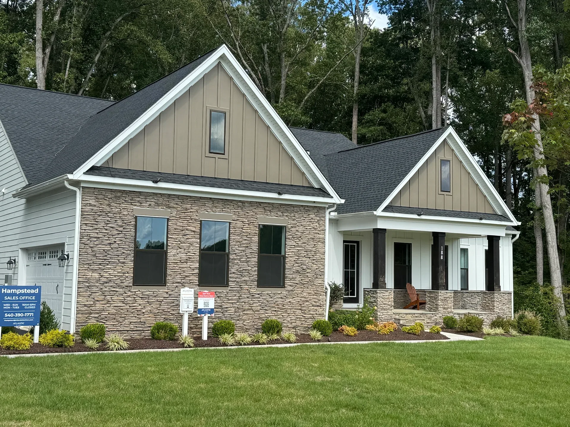 The Torrey model sales home at the Atlantic Builders sales center, a modern farmhouse-style new construction home with tan and white siding, stone accents, and a covered front porch