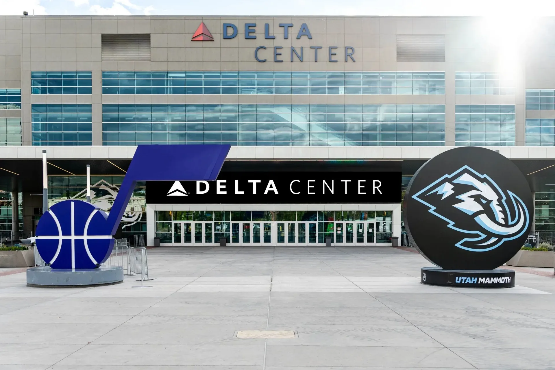 The Delta Center exterior in downtown Salt Lake City, with the Utah Jazz logo sculpture and the Utah Mammoth arena sign out front