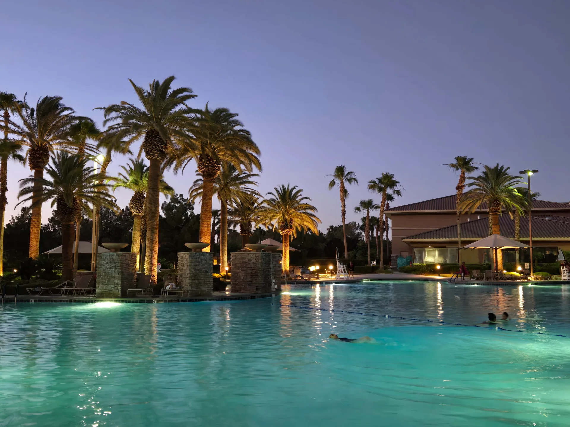 Martin's photo of the resort-style swimming pool at Rhodes Ranch at twilight with palm trees and stone water features lit up