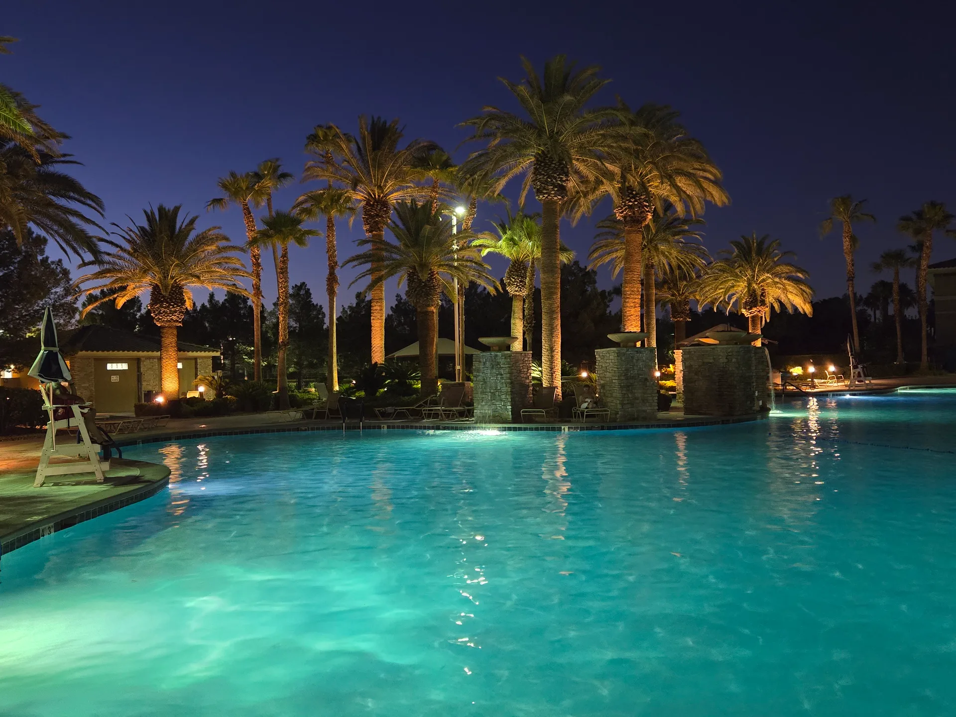 Martin's photo of the resort-style swimming pool at Rhodes Ranch at night with illuminated palm trees and glowing blue water