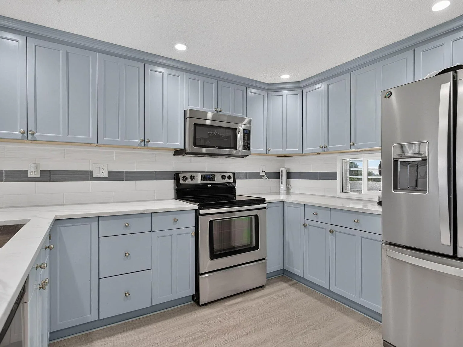 Remodeled kitchen with custom-painted cabinets, quartz counters, and stainless appliances