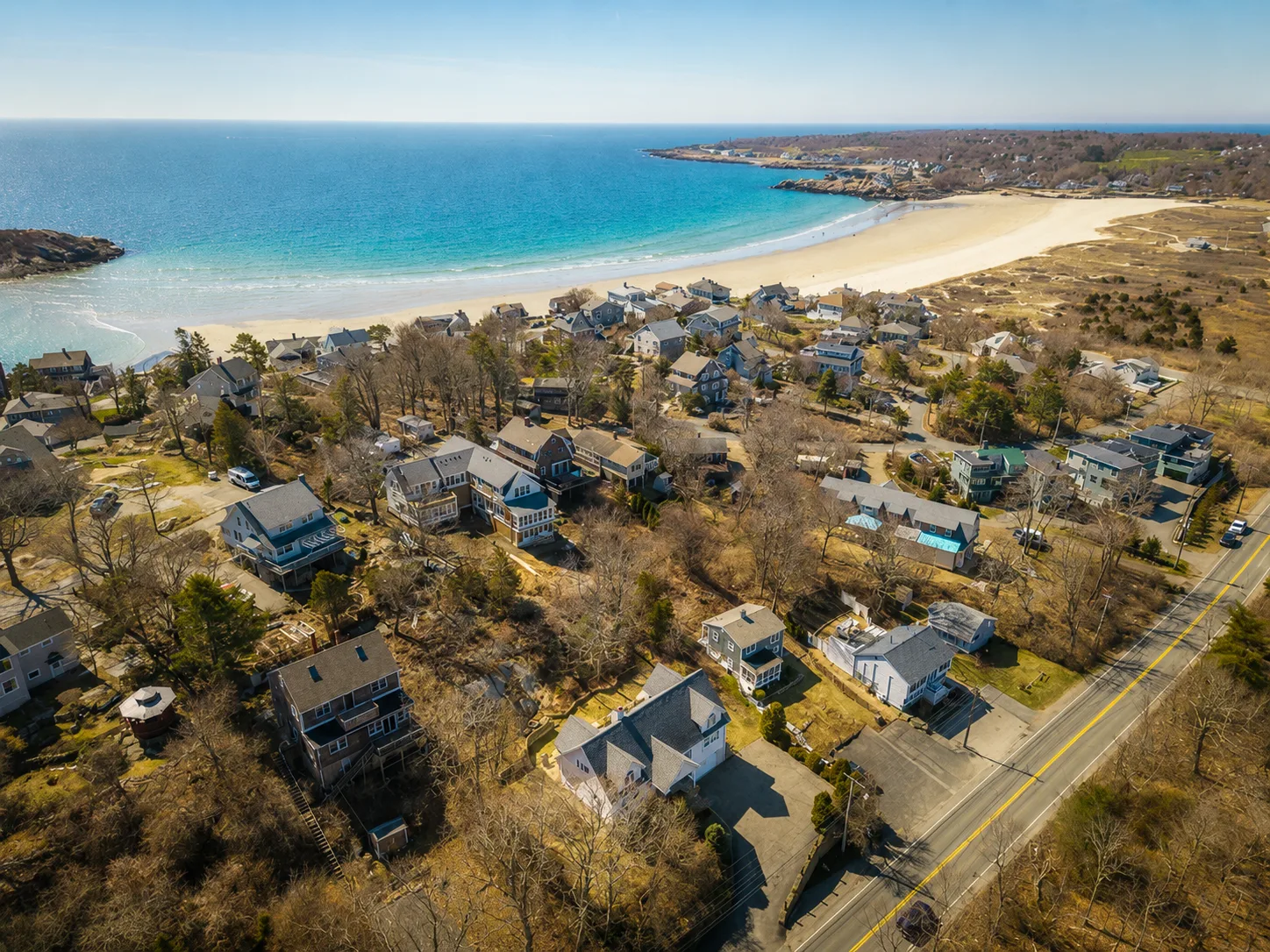 Aerial view of a coastal North Shore neighborhood where sandy beach meets the ocean