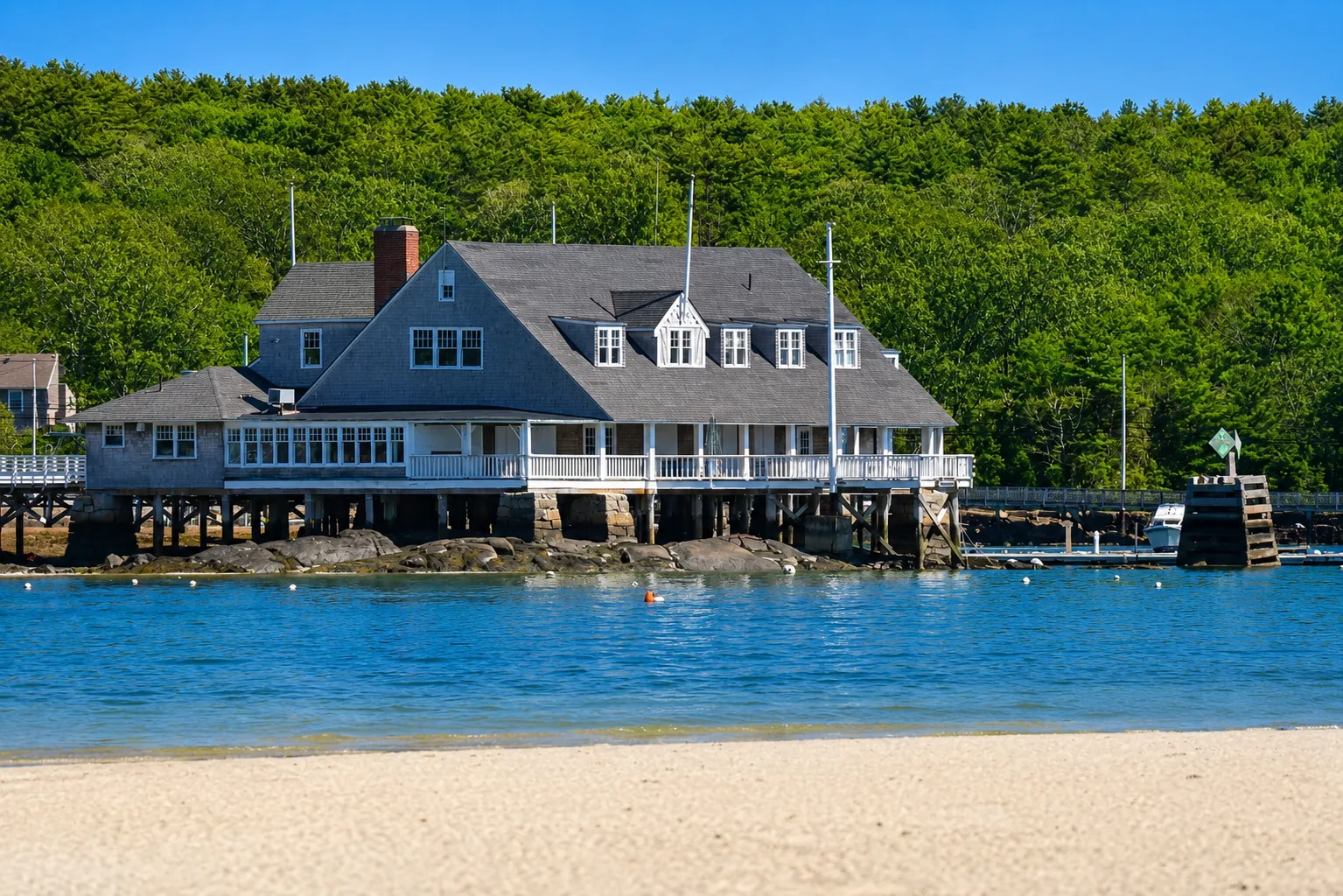 Shingle-style coastal home built into a rocky shoreline on the North Shore