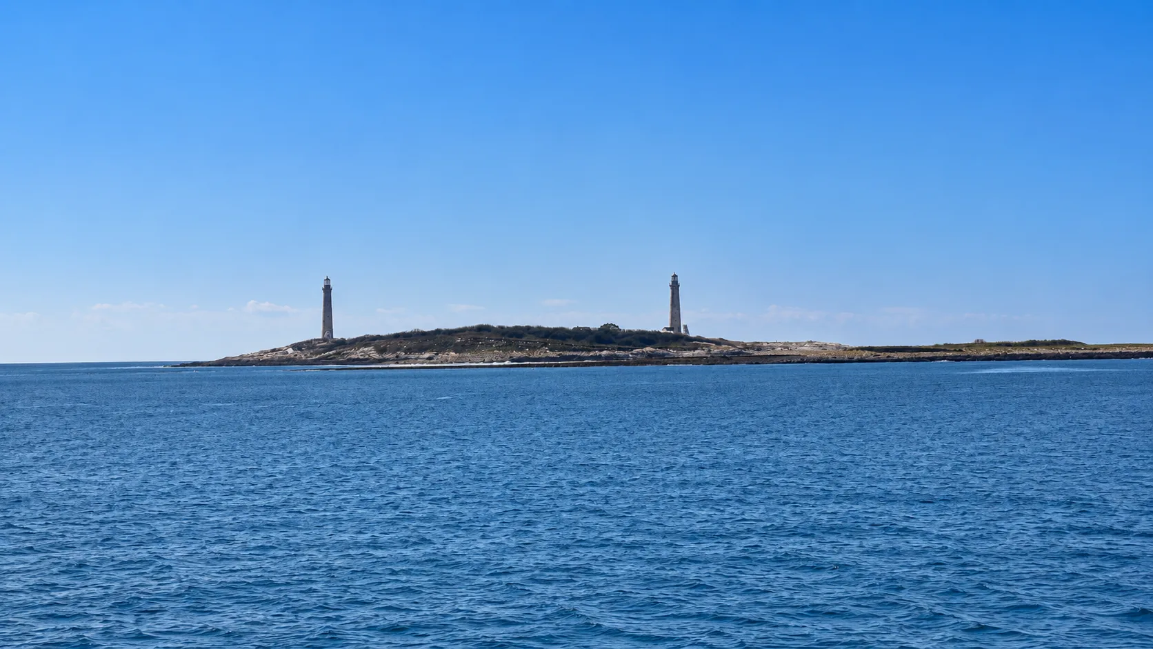 Two lighthouses on a small island off the North Shore coast, seen from across the water