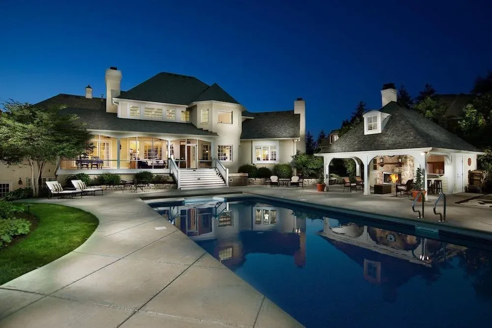 Luxury backyard pool and patio at twilight with warm landscape lighting