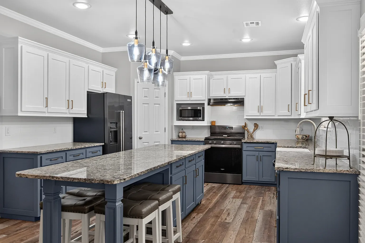 Kitchen island with white upper cabinets and stainless appliances