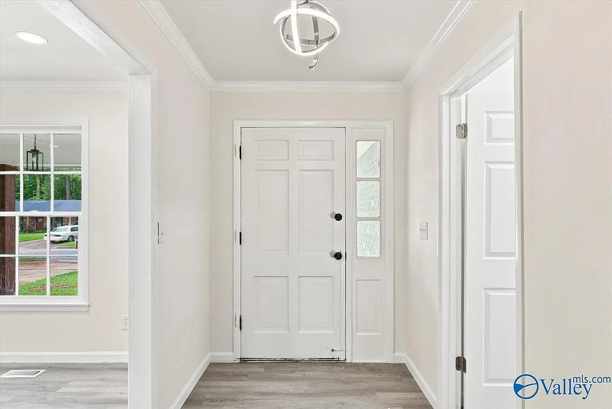 Front entryway with crown molding and plank flooring, looking toward the front door