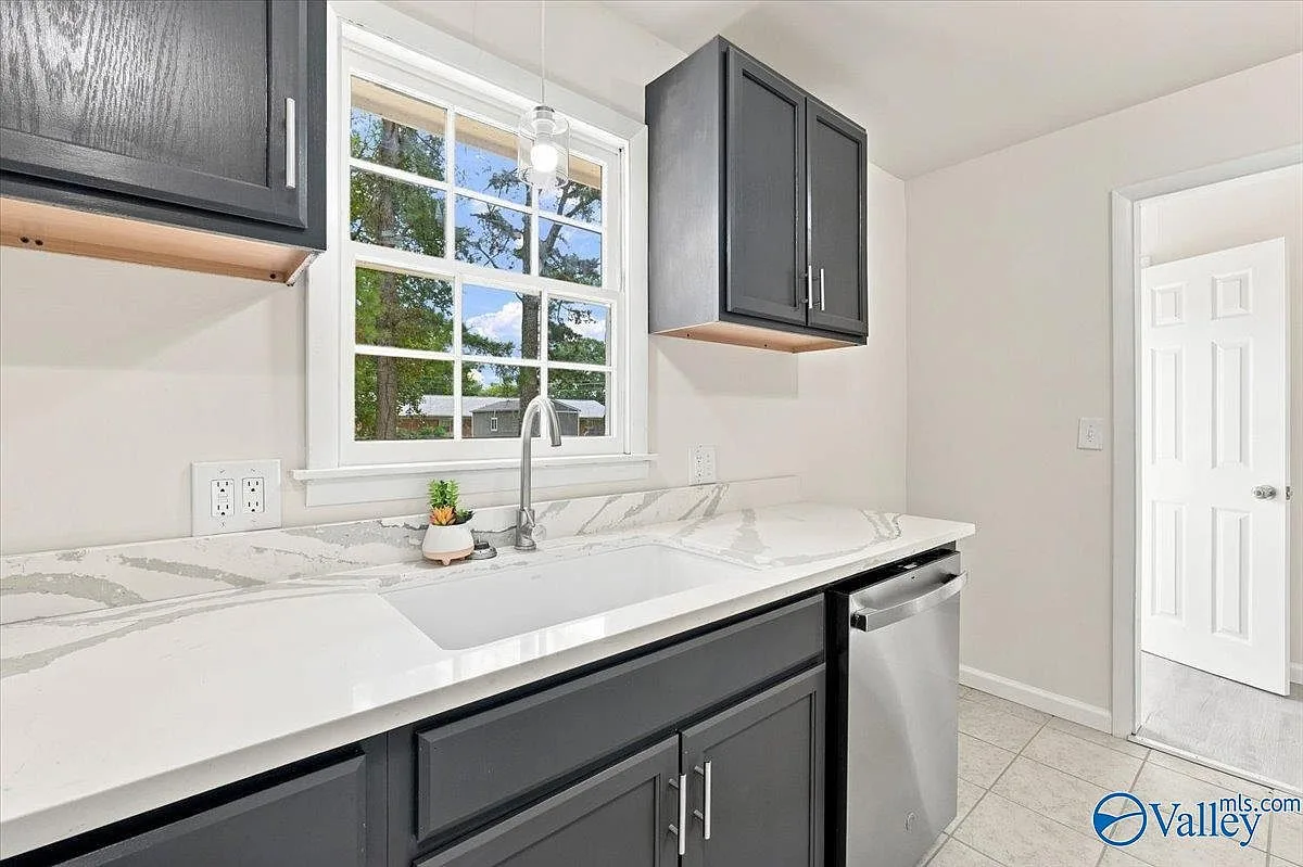 Kitchen sink area with quartz countertop, window, and pendant light